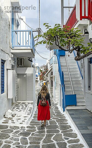 Junge Frau mit rotem Rock in den Gassen der Altstadt Chora  Kykladische weiße Häuser mit bunten Geländern  Mykonos Stadt  Mykonos  Kykladen  Griechenland  Europa