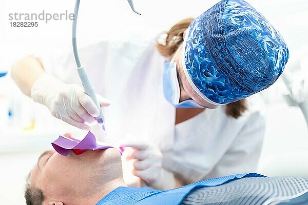 Zahnklinik  ein Arzt führt eine Wurzelbehandlung an einem Patienten in voller Aktion durch