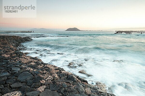 Langzeitbelichtung zum Sonnenaufgang an der Küste bei Corralejo  schöne bucht mit Steg und Lavafelsen am Morgen  Parque Natural de Corralejo  Fuerteventura  Kanarische Inseln  Spanien  Europa