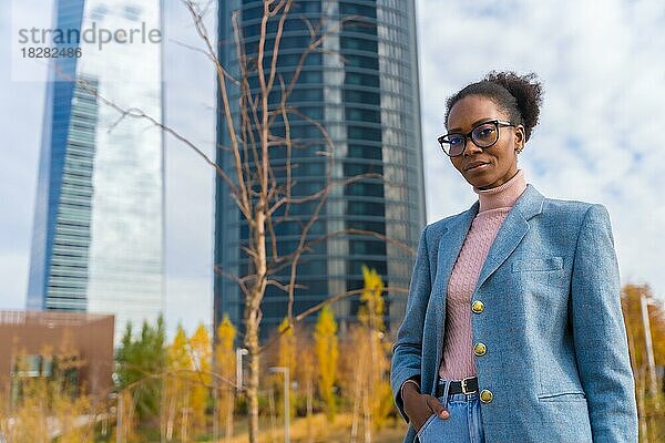 Porträt einer schwarzen ethnischen Geschäftsfrau mit Brille in einem Gewerbegebiet  die in die Kamera schaut