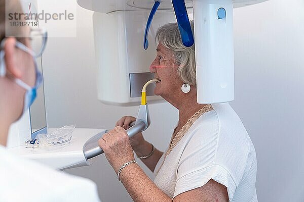 Zahnklinik  Zahnarzthelferin mit einer älteren Frau im Röntgenraum  die erklärt  wie sie die Stimme einsetzen müssen
