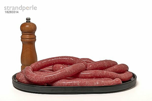 Hausgemachte Fleischwurst mit Pfefferstreuer vor weißem Hintergrund und Kopierraum