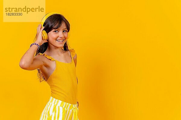Ein Mädchen hört Musik und tanzt mit drahtlosen Kopfhörern Musik-Streaming oder online  gelben Hintergrund