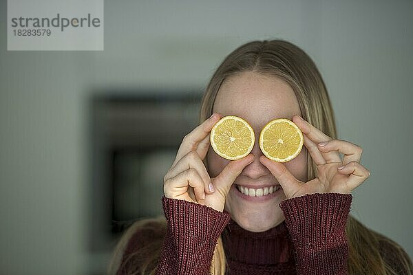 Junge Frau  schneidet Obst  albert in der Küche  hat Spaß mit Zitronen  Oberbayern  Bayern  Deutschland  Europa