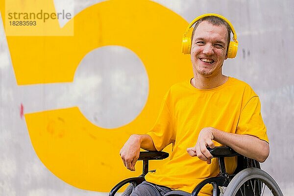 Gelb gekleidete behinderte Person in einem Rollstuhl  die lächelnd Musik hört