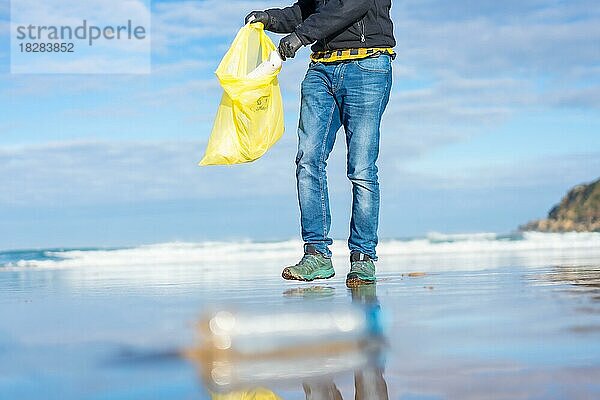 Meeresverschmutzung  nicht erkennbare Person  die am Strand Müll und Plastik sammelt. Ökologiekonzept