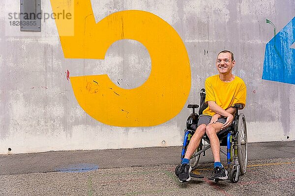 Behinderte Person in einem öffentlichen Park in einem Rollstuhl  die ein gelbes T-Shirt trägt und lächelt