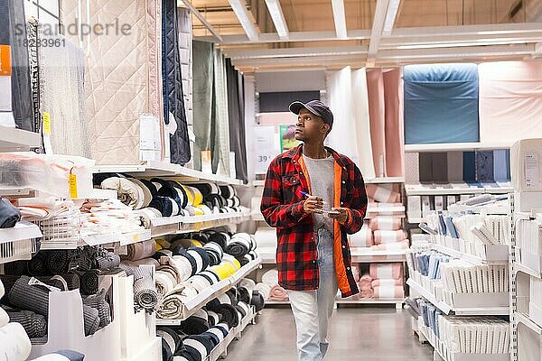 Schwarzer ethnischer Mann beim Einkaufen in einem Supermarkt für Badematten und Handtücher