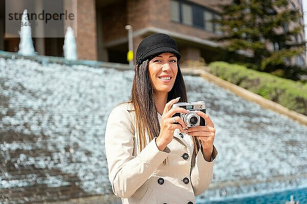 Eine Touristin  die während ihres Sommerurlaubs in der Stadt neben einem Brunnen Fotos macht