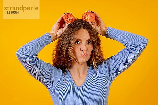 Vegane Frau mit Tomatenscheiben auf dem Kopf auf einem gelben Hintergrund  vegetarisches Leben