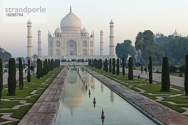 Das Taj Mahal und seine Spiegelung im Wasserkanal. Eine klassische Wintermorgenansicht des Mausoleums  beleuchtet von den weichen  pastellfarbenen Strahlen der aufgehenden Sonne  die von der rechten Seite des Bildes scheint. Weltwunder  UNESCO-Weltkulturerbe  berühmtes Wahrzeichen und Touristenattraktion. Agra  Uttar Pradesh  Indien  Asien
