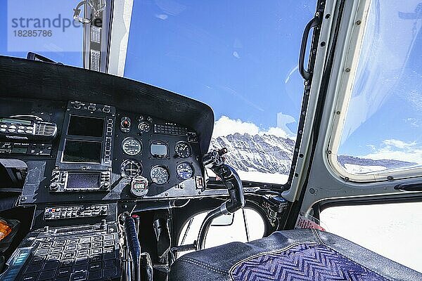 Cockpit im Inneren des Hubschraubers  Instrumente  Steuerknüppel  Parks auf dem Aletschgletscher. Blick durch Hubschrauberfenster ist gegen den blauen Himmel mit Wolken und Berg. Jungfrau Joch  Eiger  Schweizer Alpen  Schweiz  Europa