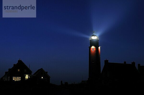 Häuser und Lichtstrahlen von der Laterne des Leuchtturms Cocksdorp Eierland bei Nacht  Texel  die Niederlande