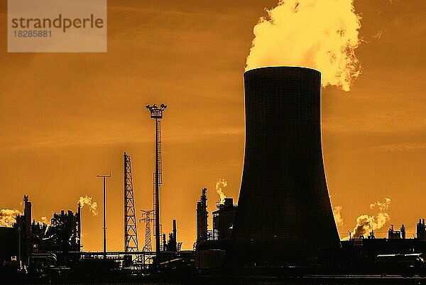 Industriegebiet mit Kühlturm als Silhouette im Sonnenuntergang auf dem Gelände der BASF-Chemieproduktion im Hafen von Antwerpen  Belgien  Europa