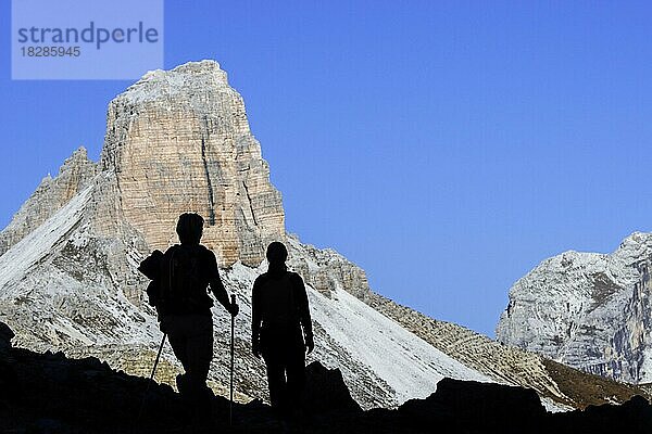 Zwei Bergwanderer vor der Silhouette des Torre dei Scarperi  Schwabenalpenkopf  Sextner Dolomiten  Parco Naturale Tre Cime  Südtirol  Italien  Europa