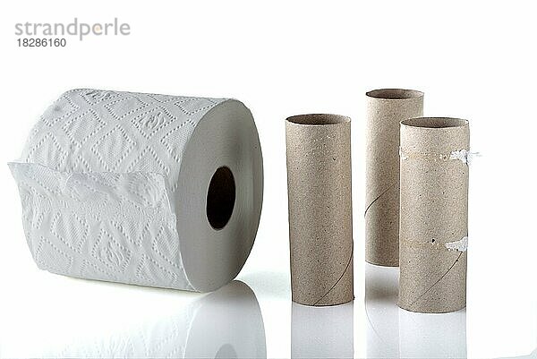 Drei leere Toilettenpapierrollen neben einer neuen vollen Rolle