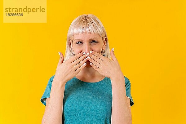 Blowing a kiss with both hands  blonde kaukasische Mädchen im Studio auf gelbem Hintergrund