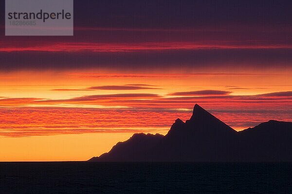 Berg am Kongsfjorden im Schatten eines farbenprächtigen Sonnenuntergangs im Sommer  Spitzbergen  Norwegen  Europa