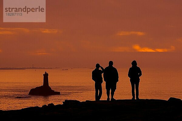 Touristen  die den Leuchtturm La Vieille in der Meerenge Raz de Sein im Schatten des Sonnenuntergangs an der Pointe du Raz  Plogoff  Finistère  Bretagne  Frankreich  beobachten  Europa