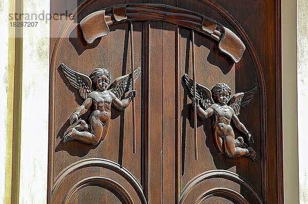 Alte Haustür aus Holz mit angebrachter Holzschnitzerei in Form von schwebende Engel zwei Engeln mit Flügeln  Insel La Maddalena  Sardinien  Italien  Europa