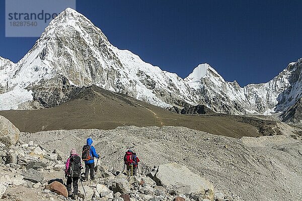 Wanderer beim Überqueren der Gletschermoränen auf dem Weg zum Everest-Basislager in der Nähe von Gorakshep im Khumbu-Tal in der Everest-Region. Der Pumori befindet sich auf der linken Seite und der Kala Patthar  einer der besten Aussichtspunkte im Himalaya  liegt darunter. Khumbu-Region  Sagarmatha-Nationalpark  Solukhumbu  Nepal  Asien