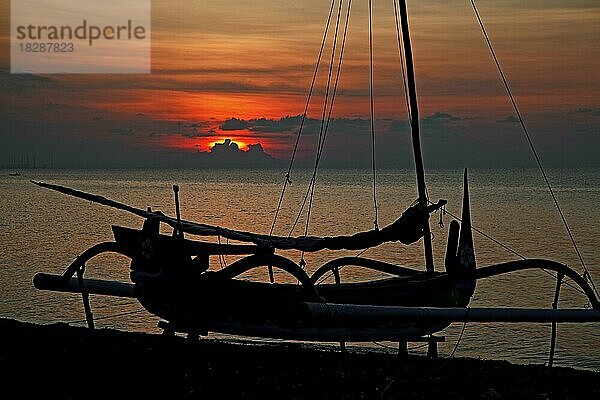 Silhouette eines indonesischen Jukung  eines traditionellen hölzernen Auslegerkanus am Strand entlang des Indischen Ozeans bei Sonnenuntergang  West Java  Indonesien  Asien