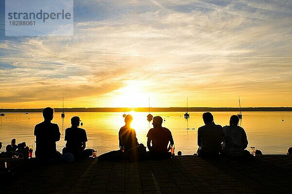 Silhouetten von Menschen beim Sonnenuntergang am Ufer des Ammersees  Bayern  Deutschland  Europa