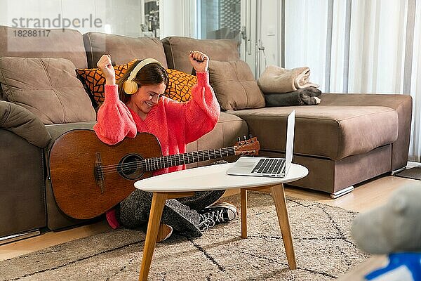 Frau lernt zu Hause Gitarre spielen  sehr glücklich  weil sie das Lied gut gespielt hat