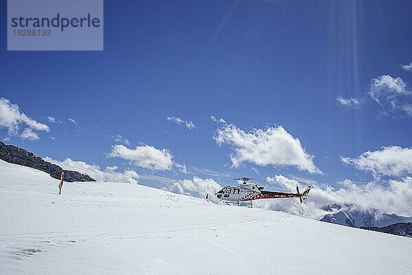 Rot-weißer Schweizer Hubschrauber parkt auf dem Aletschgletscher. Der Hubschrauber ist gegen den blauen Himmel mit Wolken. Jungfrau Joch  Eiger  Schweizer Alpen  Schweiz  Europa