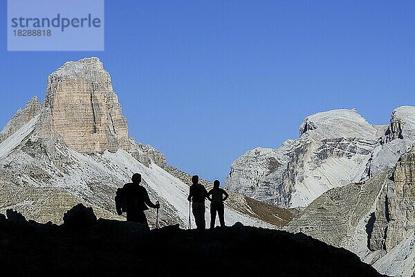 Drei Bergwanderer vor der Silhouette des Torre dei Scarperi  Schwabenalpenkopf  Sextner Dolomiten  Parco Naturale Tre Cime  Südtirol  Italien  Europa