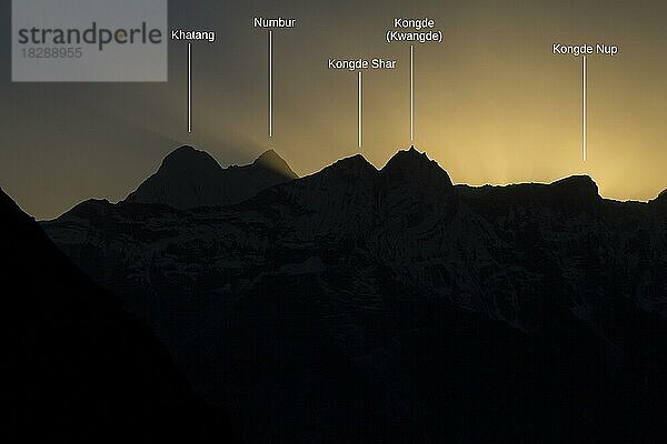 Kongde und andere Gipfel des Rolwaling Himal im Gegenlicht der untergehenden Sonne  gesehen von einer Stelle unterhalb des Ama Dablam Base Camps  oberhalb von Pangboche. Ein Foto mit beschrifteten Gipfeln  aufgenommen in der Everest-Region während der Herbsttrekking-Saison. Sagarmatha-Nationalpark  Khumbu-Region  Himalaya. Solukhumbu  Nepal  Asien