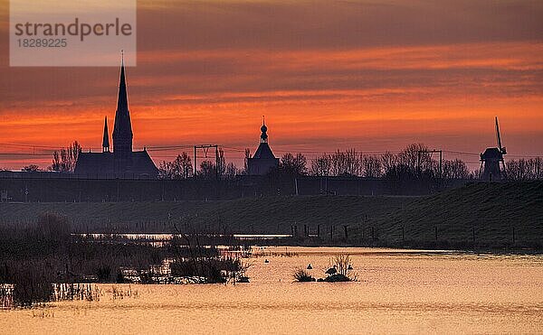 Glockenturm  Torturm und Windmühle der Stadt Culemborg als Silhouette bei Sonnenaufgang im Winter  Gelderland  die Niederlande