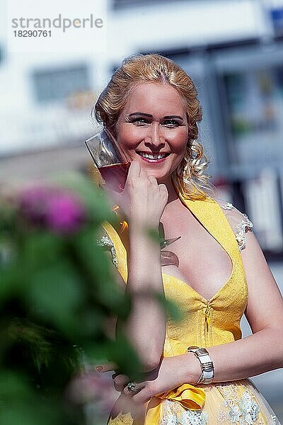 Porträt einer Frau im Dirndl mit einem Glas Sekt in der Hand