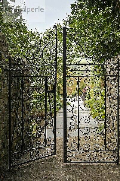 Ein Paar schmiedeeiserne Tore  die in einen typisch englischen  angelegten Garten führen