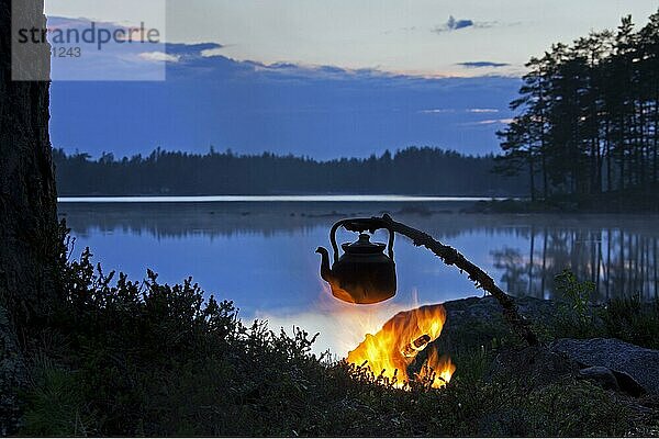 Kessel zum Kaffeekochen  der über einem offenen Lagerfeuer am See bei Sonnenuntergang erhitzt wird  Dalarna  Schweden  Europa