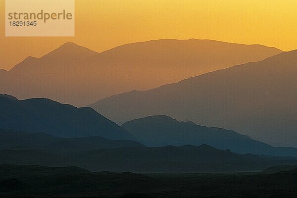 Silhouetten von aufeinanderfolgenden Hügeln und Bergen bei Sonnenuntergang in den schottischen Highlands  Schottland  UK