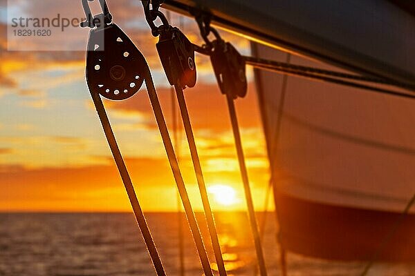 Nahaufnahme von Segelboot Blöcke  Segelboot Rollen silhouetted gegen orange Sonnenuntergang Himmel über dem Karibischen Meer