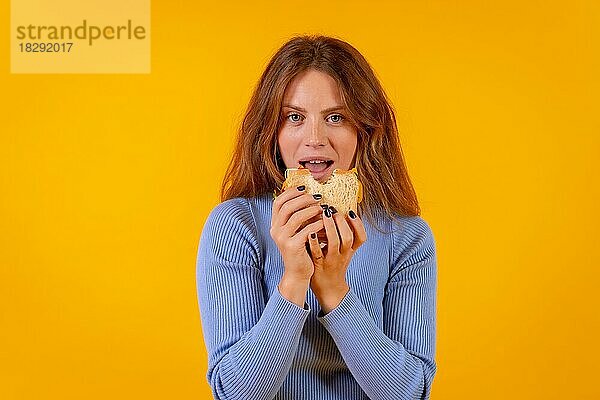 Vegetarische Frau isst ein Sandwich auf einem gelben Hintergrund  gesundes vegetarisches Essen