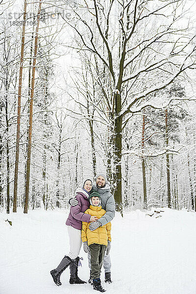 Glückliche Familie umarmt sich im Schnee im Winterpark