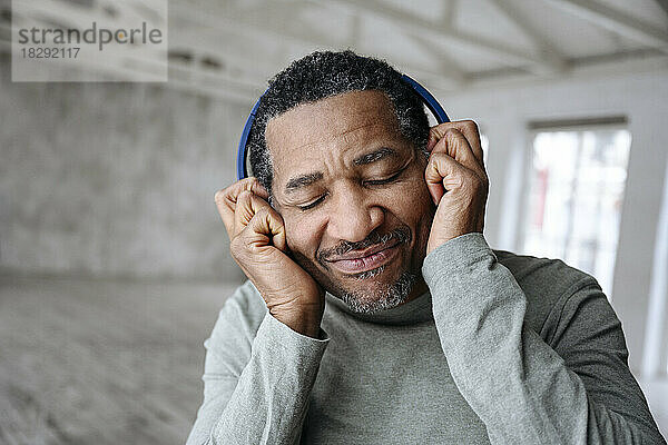 Mann genießt Musik und hört zu Hause über kabellose Kopfhörer