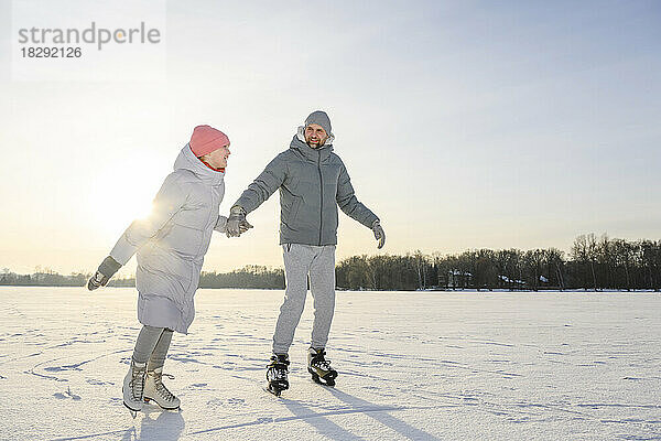 Glückliche Tochter mit Vater beim Eislaufen auf dem Wintersee