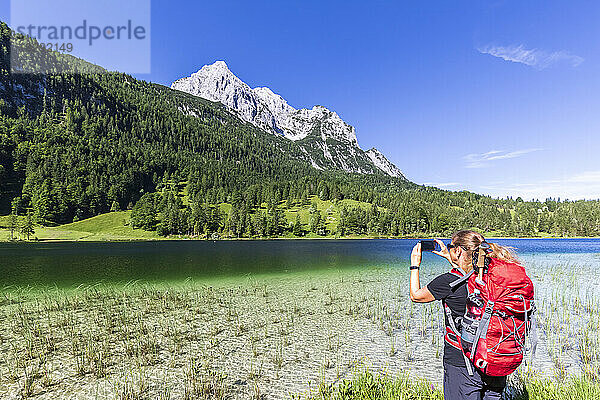 Germany  Bavaria  Female hiker photographing Ferchensee lake in summer