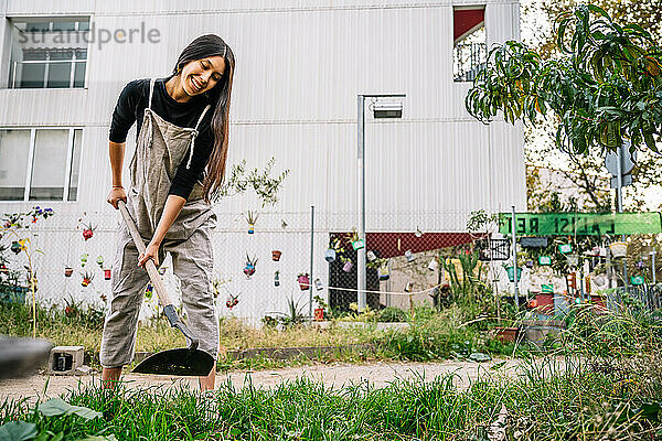 Glückliche junge Frau arbeitet mit Schaufel im Stadtgarten