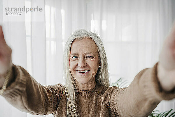 Lächelnde reife Frau  die zu Hause ein Selfie macht