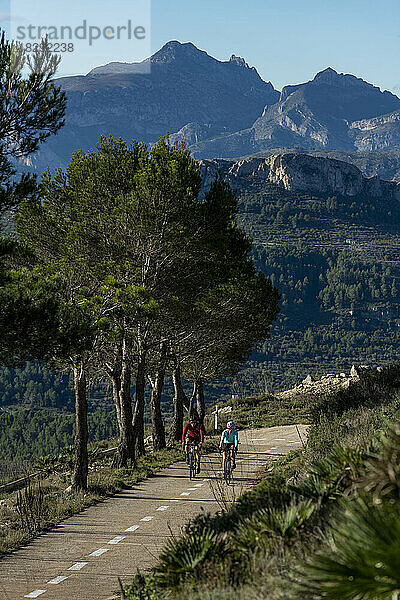 Radfahrer fahren gemeinsam mit dem Fahrrad auf der Straße vor den Bergen