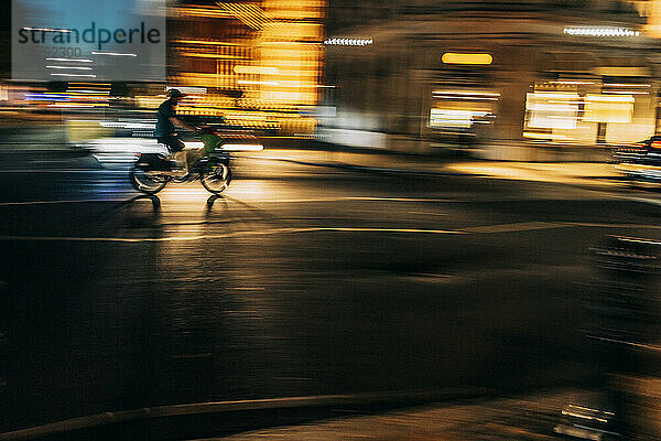 Großbritannien  England  London  verschwommene Bewegung einer Person  die nachts Motorrad entlang der Stadtstraße fährt