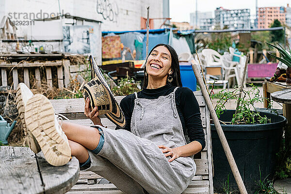 Cheerful woman sitting on bench in urban garden