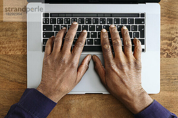 Hände eines Geschäftsmannes mit Laptop auf dem Schreibtisch