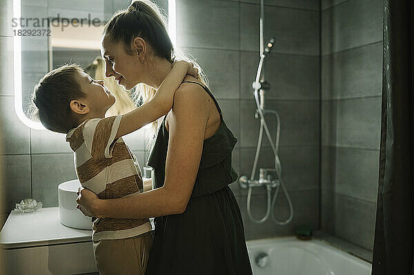 Smiling mother embracing son in bathroom at home