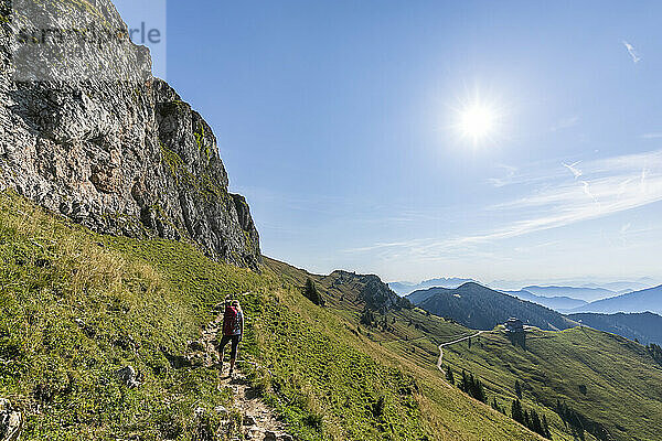 Deutschland  Bayern  Sonne scheint über einer Wanderin  die dem Weg zum Gipfel der Rotwand folgt